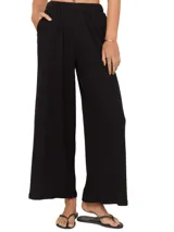 Pantalón negro de tejido acanalado, corte ancho y cintura elástica.