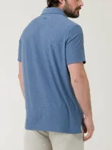 Remera polo azul jaspeado con bolsillo en el pecho y botones en el cuello. Confeccionada con fibras recicladas y spandex con tecnología Natural Flex.