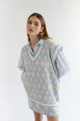 Chaleco tejido de lana con patrón de rombos en tonos lila, rojo y beige, con cuello en V y ribetes en color crema. Diseño oversize.