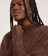 Suéter marrón de punto con cuello redondo y mangas largas ajustadas. Diseño slim alargado con efecto de pelitos.