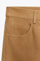 Pantalón de cuero color camel, de tiro alto, corte recto y bolsillos delanteros y traseros.