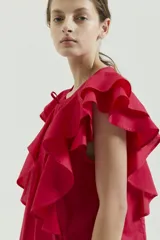 Top de voile liso color fucsia, sin mangas, con escote redondo y tajo pequeño en el centro. Tiene detalle de alforzas finas a cada lado del tajo y dos volados superpuestos que continúan de adelante hacia atrás.