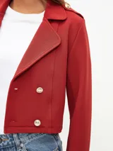 Chaqueta corta negra con doble botonadura dorada, cuello solapa y textura acanalada.