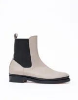 Bota Chelsea de cuero color gris claro con elástico lateral negro y suela de cuero negra.