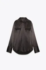 Camisa negra satinada de cuello solapa y manga larga. Tiene dos bolsillos con solapa en el delantero, bajo asimétrico y cierre frontal con botones.