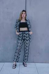 Conjunto de tres piezas con estampado floral blanco sobre fondo negro, compuesto por un top bandeau negro, una camisa de manga corta con cuello solapa y un pantalón largo de corte recto.