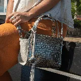 Cartera de cuero vacuno con diseño en crocco dorado y arena, con dos manijas cortas y correa larga ajustable.