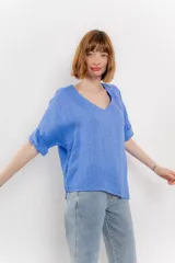 Blusa color naranja confeccionada en 100% lino, con escote en V, mangas cortas con vuelta y silueta amplia. Presenta terminación asimétrica y fila de botones decorativos en uno de los hombros.