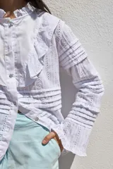 Camisa blanca de algodón con cuello mao, volados en el frente y mangas largas con puños abotonados.