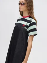 Vestido midi de denim algodón color marrón, con escote recto y tirantes finos ajustables con lazos. El corte es suelto y termina con un ruedo con semi-volado.