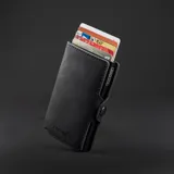 Billetera negra de cuero con caja de aluminio incorporada con sistema de deslizamiento para tarjetas, protección RFID, espacio para 5 tarjetas, sección para hasta 7 billetes y espacio adicional para libreta de propiedad y de conducir.