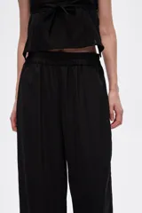 Pantalón negro de viscosa, corte ancho y tiro alto, con elástico en la cintura y bolsillos laterales.