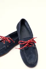 Mocasín tipo boat shoe con estampado de vaca en tonos marrón y blanco, confeccionado en cuero. Cuenta con cordones de cuero marrón oscuro y suela de goma.