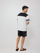 Remera blanca de hombre con corte negro en la parte superior del pecho y mangas cortas con tres rayas horizontales negras. Estampado frontal con el logo de Rusty en negro y la palabra 'Culture' en rojo.