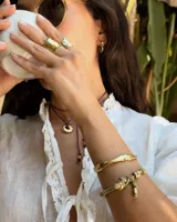 Brazalete rígido abierto de bronce con textura irregular.