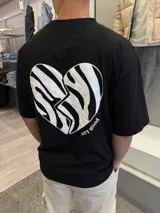 Remera negra de algodón con corte oversize y estampado de un corazón roto con diseño de cebra y la frase "very good" en la espalda.