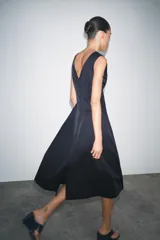 Vestido midi azul marino confeccionado en hilatura con algodón. Escote pico y tirantes anchos. Bajo evasé. Cierre frontal con cremallera metálica.