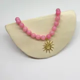 Collar elaborado con bolitas de 10 mm de diámetro de Ágata teñida de color rosa, con separadores de hilo rosado y dije de sol con baño de oro.