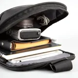 Bandolera negra de poliéster y simil cuero, con diseño ultrafino y ligero. Cuenta con correas reforzadas para uso izquierdo o derecho, bolsillo delantero con velcro, bolsillo trasero antirobo con cierre y espacio para tablets de hasta 7 pulgadas.