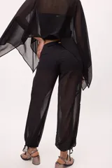 Pantalón negro traslúcido con corte ancho y ajuste en los tobillos.