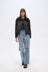 Campera negra de estilo aviador, confeccionada en material tipo gamuza o suede, con cuello y forro de corderito (shearling) negro. Presenta cierre frontal metálico y puños y ruedo con terminación de corderito.