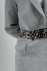 Cinturón de cuero color marrón claro con hebilla metálica plateada y apliques de tachas redondas y cuadradas.