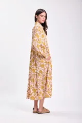 Vestido midi de corte holgado con estampado floral en tonos rosa y amarillo. Tiene cuello camisero, mangas largas con puños elásticos y falda escalonada.