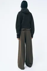 Pantalón de tiro medio color verde oliva, con cintura con trabillas, bolsillos laterales ocultos, cinturón ajustable con hebilla metálica, pinzas delanteras y cierre frontal con cremallera, botón y gancho metálico.