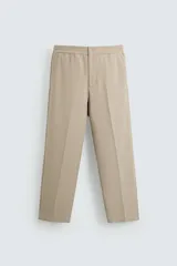 Pantalón de vestir color beige, de corte recto, con cintura elástica, bolsillos laterales y un bolsillo trasero de ojal.