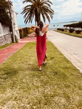 Vestido de fiesta fucsia con escote y espalda de cuero, tajos laterales con hilo metálico y terminación con flecos.