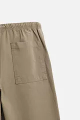 Pantalón de hombre color beige, corte carrot fit, con cintura elástica ajustable con cordón, bolsillos frontales y bolsillo trasero de plastrón.