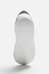 Zapatillas deportivas negras con detalle en blanco en la parte posterior y suela blanca con volumen de diseño irregular.