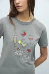 Remera gris con cuello redondo y estampado de copas de cóctel con la frase "Cocktail Club".