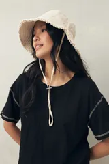 Remera blanca de algodón liviano, de manga corta y cuello redondo. Presenta costuras a contratono visibles en hombros y mangas.