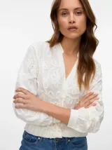 Camisa blanca de manga larga con cuello en V, cierre frontal con botones, puños abotonados y bordado floral.