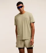 Bermuda deportiva color verde claro con short de compresión interno negro, cintura elástica con cordón ajustable y detalle reflectante trasero.