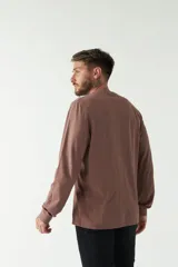 Remera color marrón de manga larga, con bolsillo en el pecho y logo de la marca en etiqueta sobre el bolsillo.