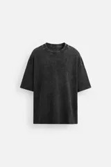 Camiseta negra de corte amplio, confeccionada en algodón con cuello redondo y mangas cortas. Tiene un efecto lavado que le da una apariencia única.