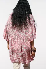 Vestido corto con estampado floral en tonos rosados, escote en pico y mangas abullonadas.