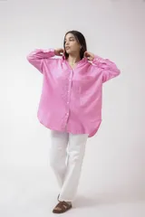 Camisa blanca de lino, de corte holgado, con cuello clásico, cierre frontal con botones, bolsillo en el pecho y mangas largas con puños abotonados.