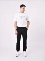 Pantalón jogger gris oscuro con cintura elástica ajustable con cordón, bolsillos laterales y bolsillo cargo con solapa en la pierna. Puños elásticos en los tobillos.