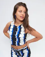 Top corto con estampado geométrico en azul, blanco y negro, de cuello redondo y corte halter. Presenta cierre lateral y abertura con botón en la espalda.