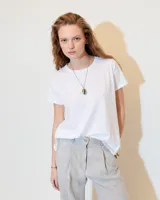 Remera blanca de jersey flama 100% algodón, de línea A y fit relajado, con escote redondo a la base, manga corta y recortes a los costados, tanto en delantero como en espalda.