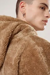 Hoodie beige de piel de corderito sintético, corte oversize con cierre central al estilo anorak, capucha con cordón ajustable y bolsillo canguro.