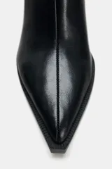 Botín de cuero negro con punta fina, cierre de cremallera lateral y tacón ancho geométrico.