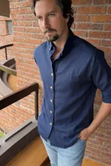 Camisa de manga larga color azul marino, con cuello abotonado (button-down) y botones claros. Presenta un pequeño logo bordado en el pecho izquierdo.
