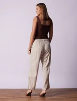 Pantalón largo de lino y rayón a rayas verticales grises y blancas. Tiene pretina elastizada con lazo de ajuste, bolsillos delanteros y traseros.