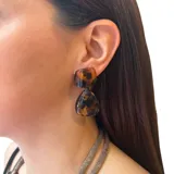 Aros colgantes con forma geométrica, con pieza superior cuadrada y pieza inferior triangular, con diseño carey en tonos negro, marrón y amarillo.