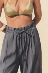 Pantalón gris de tejido fluido, tiro alto con cintura tipo paper bag, bolsillos laterales y cinturón lazada en el mismo tejido.