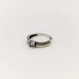Anillo de plata 925 con detalles en oro y circonias. Presenta una circonia central cuadrada y circonias pequeñas en el lateral. No es ajustable.